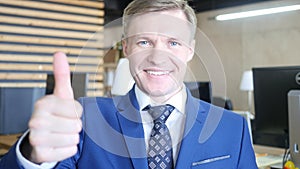 Businessman showing OK sign with his thumb up. Selective focus on face.
