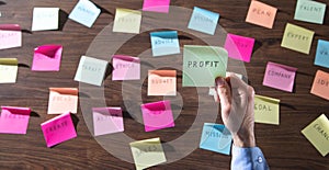 Businessman showing Profit word in sticky note. Working in office