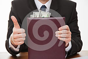Businessman showing thumb up and bribe photo