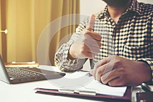 Businessman showing thumbs up in his workplace.Tump up concept