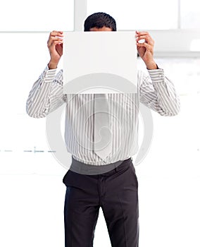 Businessman showing a white card covering his face