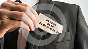 Businessman showing a wooden card reading Ask an expert