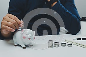 Businessman is shown holding a jar with coins for savings and investments. Concept of tax payments and business accounting