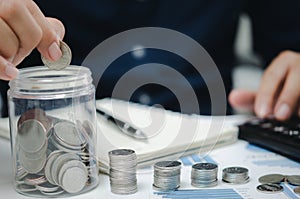 Businessman is shown holding a jar with coins for savings and investments. Concept of tax payments and business accounting