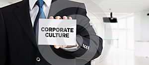 Businessman shows a business card with the message corporate culture. Business culture, core company values