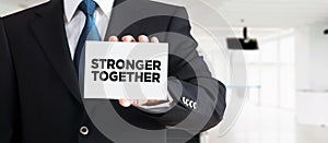 Businessman shows a business card with the message stronger together. Business teamwork