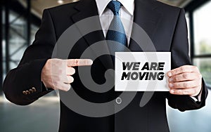 Businessman shows a card with the message we are moving. Business or office relocation