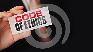 Businessman shows a card with text Code of ethics