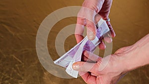 Businessman shows euro money in his hands. Golden background.