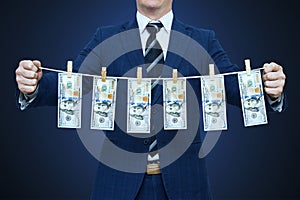 Businessman shows laundered money. Businessman holding money hanging on a rope