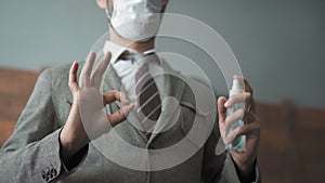 Businessman shows ok gesture holding a sanitizer or antiseptic liquid. Close up shot. Positive man in a protective mask