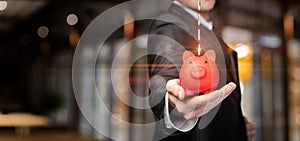 Businessman shows a piggy bank which coins are falling from a network