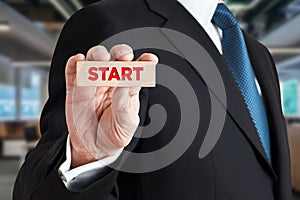 Businessman shows a wooden block with the word start