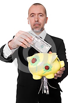 Businessman shredding dollars in a piggy bank