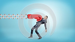 A businessman in side view gets hit with a large red boxing glove attached to a metal scissor arm on a blue background.