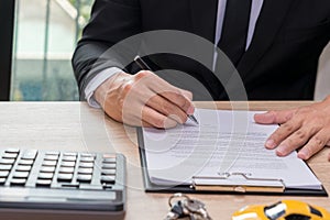 Businessman signing car loan agreement contract with car key and