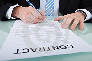 Businessman signing contract paper at office desk