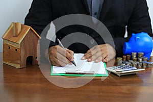 Businessman signing documents with model house, New home and real estate concept