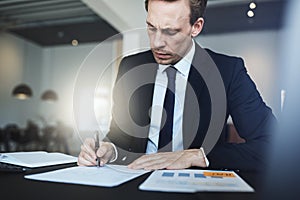 Businessman signing documents while sitting at his office desk