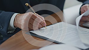 Businessman signing official documents close up. Man putting signature on papers