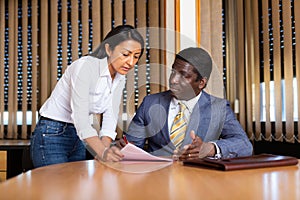 Businessman signing papers brought by female assistant