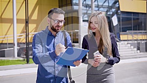 Businessman signing papers for colleague. Business man and woman working and signing the papers at office building in