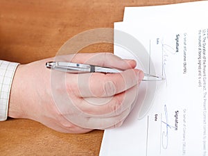 Businessman signs a contract by silver pen