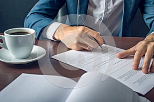 Businessman signs important legal documents on the desktop with Cup of coffee