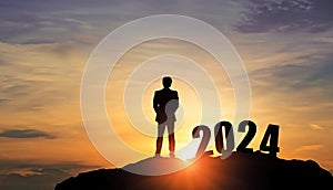 Businessman silhouette of man standing on top of the mountain with number 2024