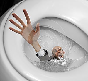 Businessman sinking in toilet bowl