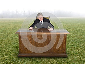 Businessman Sits At Office Desk in Field or Meadow