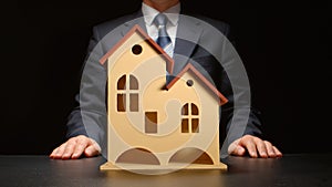 Businessman sits on a tabler near a house model