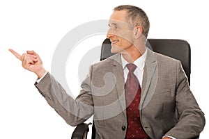 Businessman sitting on armchair and pointing left