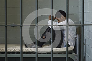 Businessman Sitting On Bed Behind Bars