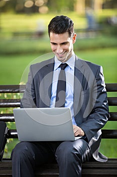 Businessman sitting on bench with laptop