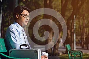 Businessman,He is sitting on bench in park.He is thinking about business.