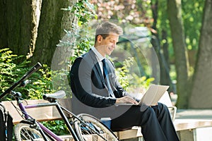 Businessman Sitting On Bench Using Laptop