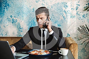 Businessman sitting in cafe using laptop computer have a breakfast or dinner eat talking by phone