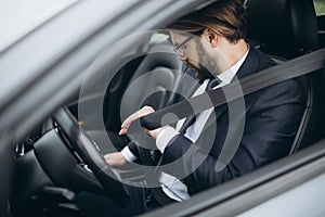 Businessman sitting in car and putting on seatbelt