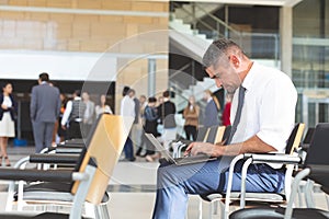 Businessman sitting on chair and using laptop in conference room