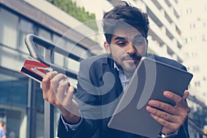 Businessman sitting on city street using digital tablet