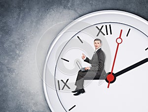 Businessman sitting on clockhand