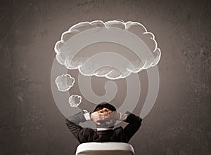 Businessman sitting with cloud thought above his head