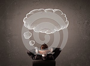 Businessman sitting with cloud thought above his head
