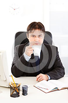 Businessman sitting at desk and drinking coffee