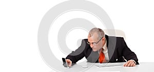 Businessman sitting at desk and holding a mobilephone with copys