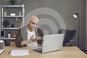 Businessman sitting at desk in home office and having online business meeting on laptop