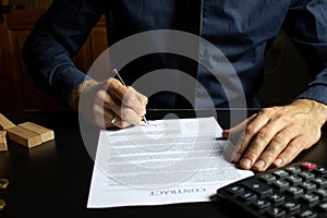 Businessman sitting at desk in home office signing contract with shallow focus on signature. Concluding a contract in a secure