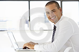 Businessman Sitting At Desk In Office Using Laptop