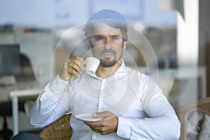 Businessman sitting down drinking an expresso coffee